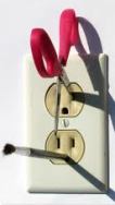 scissors and brush inserted in electrical outlet